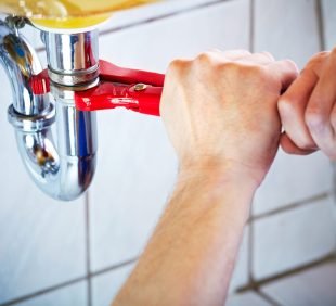 Plumber hands holding wrench and fixing a sink in bathroom Plumber hands holding wrench and fixing a sink in bathroom